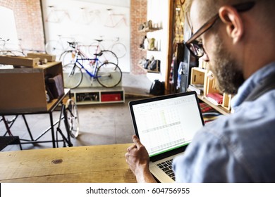 A man in a bicycle repair shop using a laptop computer Running a business - Powered by Shutterstock