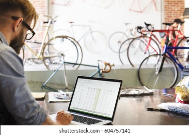 A man in a bicycle repair shop using a laptop computer Running a business - Powered by Shutterstock