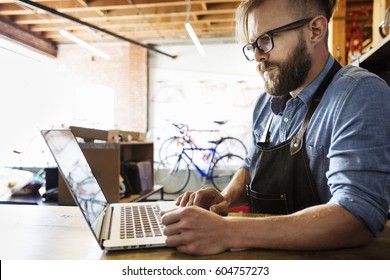 A Man In A Bicycle Repair Shop Using A Laptop Computer Running A Business