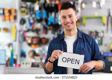 Man In Bike Shop Holding Open Sign
