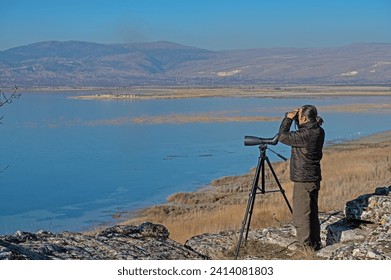 A man with binoculars bird watching on the lake. - Powered by Shutterstock