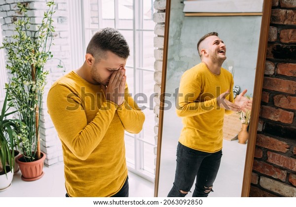 A man with bipolar disorder at the mirror. Bipolar\
affective disorder. A person with manic-depressive psychosis.\
Mental illness. A person with depression. A man is reflected in the\
mirror