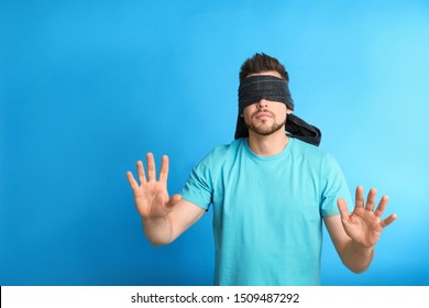 Man with black blindfold on blue background, space for text