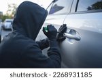 Man in black clothes with a screwdriver. He tried to break into the car. Car theft concept
