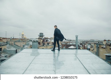 Man In Black Clothes Standing On The Edge Of The Roof