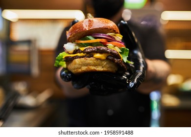 Man Black Gloves Holding Burger Hands Juicy Burger Close Appetizing burger. - Powered by Shutterstock