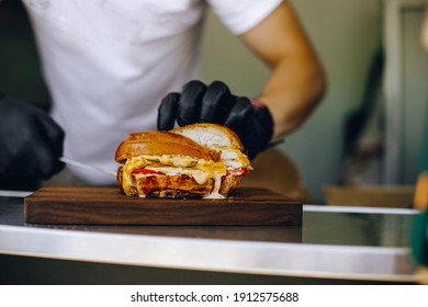 man in black gloves holds a burger cut in half - Powered by Shutterstock