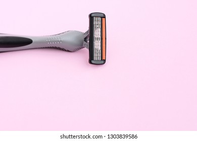Man black and grey shaving razor with selective focus on neutral background. New disposable plastic razor with steel blade for daily safety personal shaving on pink background with empty space for tex