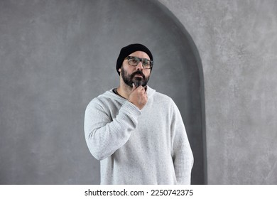 Man in black hat and white sweater with stylish glasses looking at viewer inquisitively - Powered by Shutterstock