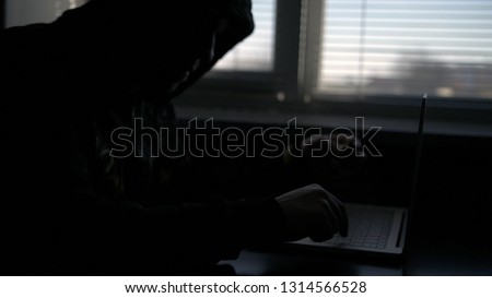 Man in black holding credit card and lock using computer laptop for criminal activity hacking bank account password and private information cracking password for illegal access.