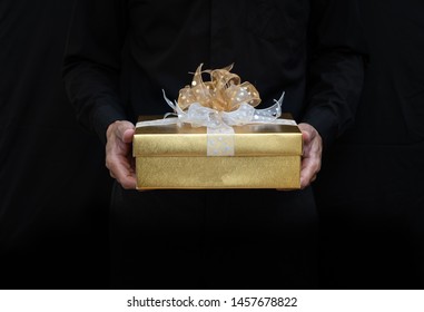 Man In Black Holding Gold Gift Box