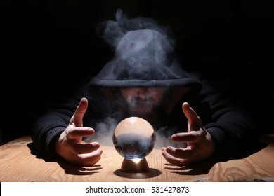man in a black hood with cristal ball summon evil