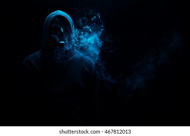 Man in black hood in the night darkness, dimly lit, concepts of danger, crime terror