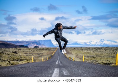 Man in black jacket and white shoes jumping with joy on an empty road in Iceland. Happy tourist jumping in the middle of the road.  - Powered by Shutterstock