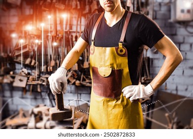 A man in a black shirt and yellow apron stands in front of a wall of tools - Powered by Shutterstock