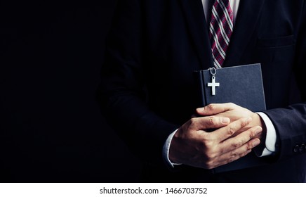 Man In Black Suit Holding Bible