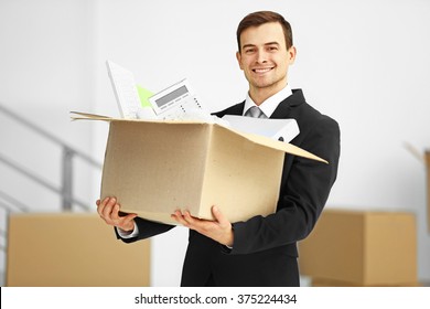 Man In Black Suit Holding Carton Box Full Of Office Stationery In The Room, Close Up