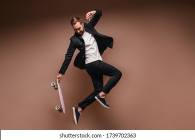 Man in black suit jumps on skateboard on brown background