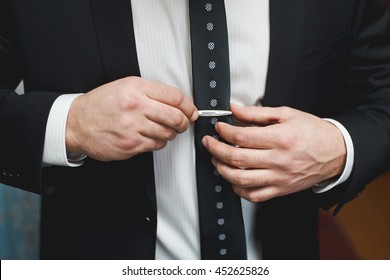 Man In Black Suit Putting On Tie Clip, Closeup