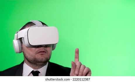 A man in a black suit uses virtual reality goggles. VR. Green background. The office worker - Powered by Shutterstock