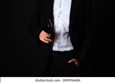 Man In A Black Suit And White Shirt With A Glass Of Wine On A Black Background