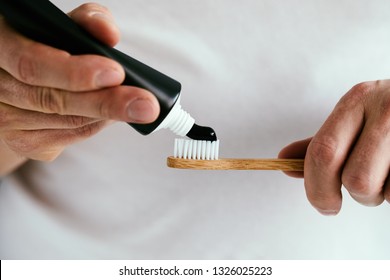 Man with a black toothpaste and a bamboo toothbrush