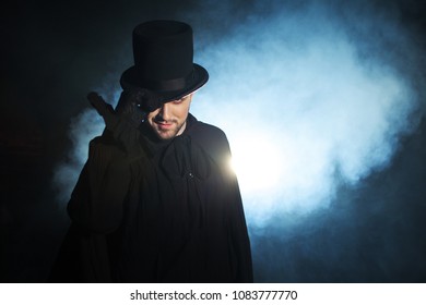 Man In A Black Top Hat And Cloak. Demonic Image. Magician Illusionist. Smoke Background