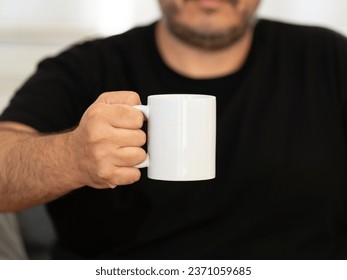 A man in black tshirt with a blank coffee mug holding in hand. Best for PSD mockup and representing your branding. A perfect white mug position for representing your design or branding.