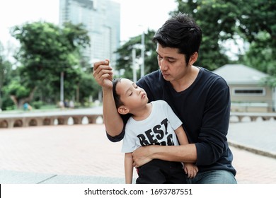 A Man In Black T-shirt Embrace His Son While He Sleep At Daytime In The Park.