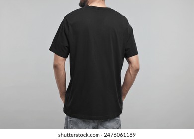 Man in black t-shirt on grey background, back view