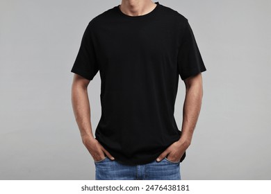 Man in black t-shirt on grey background, closeup