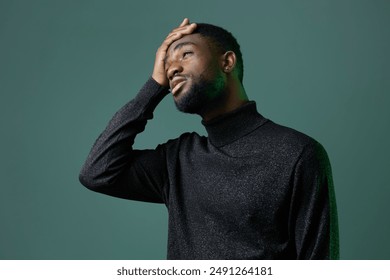 Man in black turtleneck sweater holding head with one hand, looking at camera, conveying stress or deep thought - Powered by Shutterstock