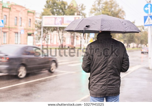 Man with black umbrella. Overcast weather.\
Blurred Background.