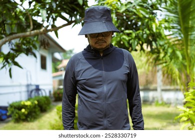 A man in black wears a black hoodie and a black hat, standing with his head bowed. - Powered by Shutterstock