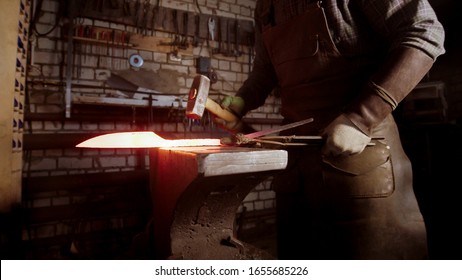 A Man Blacksmith Forging A Hot Knife Blade Using A Hammer