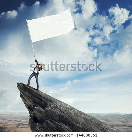 Man with blank flag standing on the top of a rock