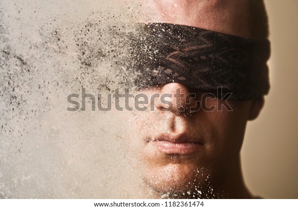 A man with a blindfold over his eyes disintegrates
into dust.