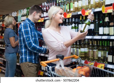 man and blonde woman buying wine in the store