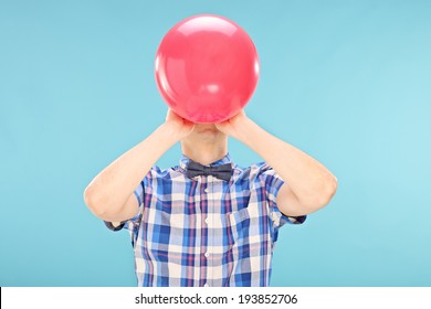 Man blowing up a balloon on blue background