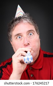 Man Blowing Noise Maker And Wearing A Party Hat