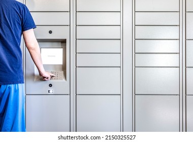 A Man In Blue Clothing Using Keypad To Get Package At The Automatic Locker In Mailroom. Modern Keyless Deliver And Pickup Parcel Of Self-service Machine, Smart Security Technology. Automated Storage.