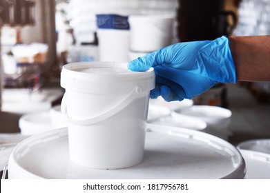 A Man In Blue Gloves Holds A Can Of Paint In His Hand. Paint Production.