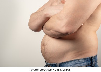 A Man In Blue Jeans With A Fat Belly And A Naked Torso On A White Background.