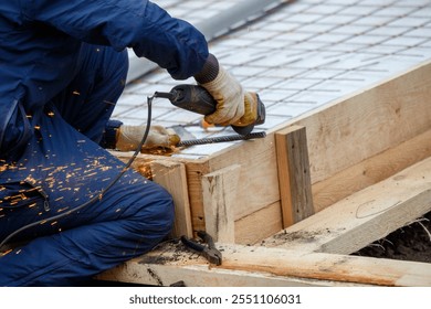 A man in a blue jumpsuit is using a power tool to cut wood. Concept of hard work and determination, as the man is focused on his task - Powered by Shutterstock