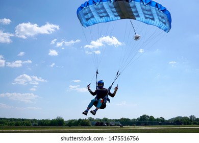 Man with a blue little canopy of a parachute is flies, close-up. High-speed landing of a Skydiver with parachuter against the background of clouds.  USA, Michigan