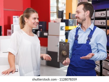 Man In Blue Overalls Showing Door Lock To Glad Female Client In Hardware Store