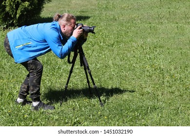 A man in blue photographs nature with a tripod.