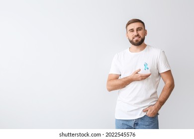 Man with blue ribbon on light background. Prostate cancer awareness concept - Shutterstock ID 2022545576