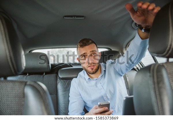 A man in a\
blue shirt in the backseat of a\
car