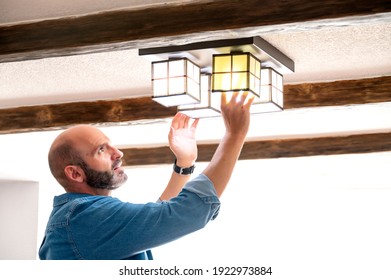 Man In Blue Shirt Changing Light Bulbs At Home